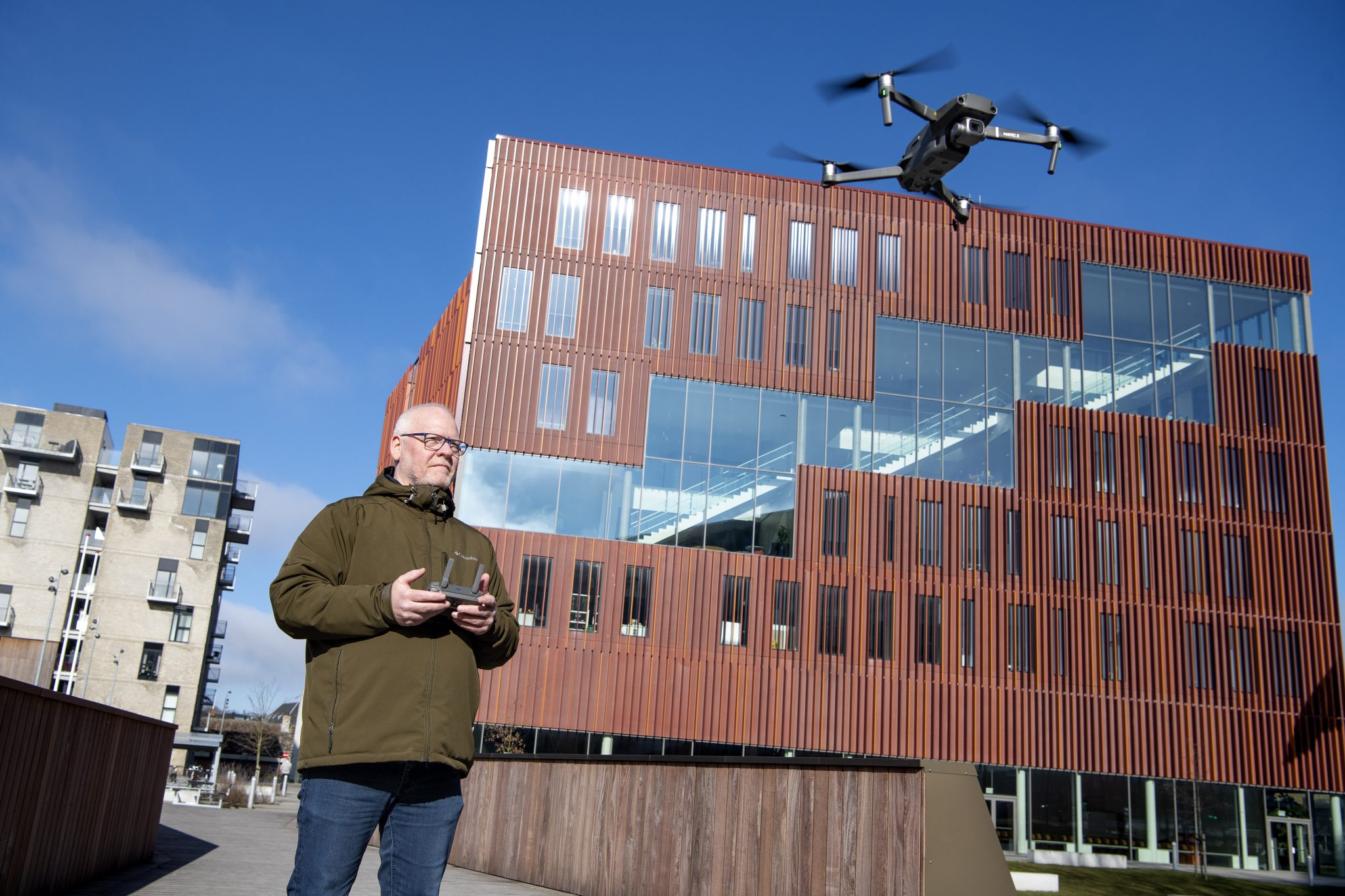 Foto af Eli Krogsholm, der flyver med en drone foran IBA's bygning