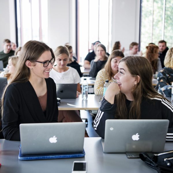 To piger der sidder i en klasse og har undervisning.