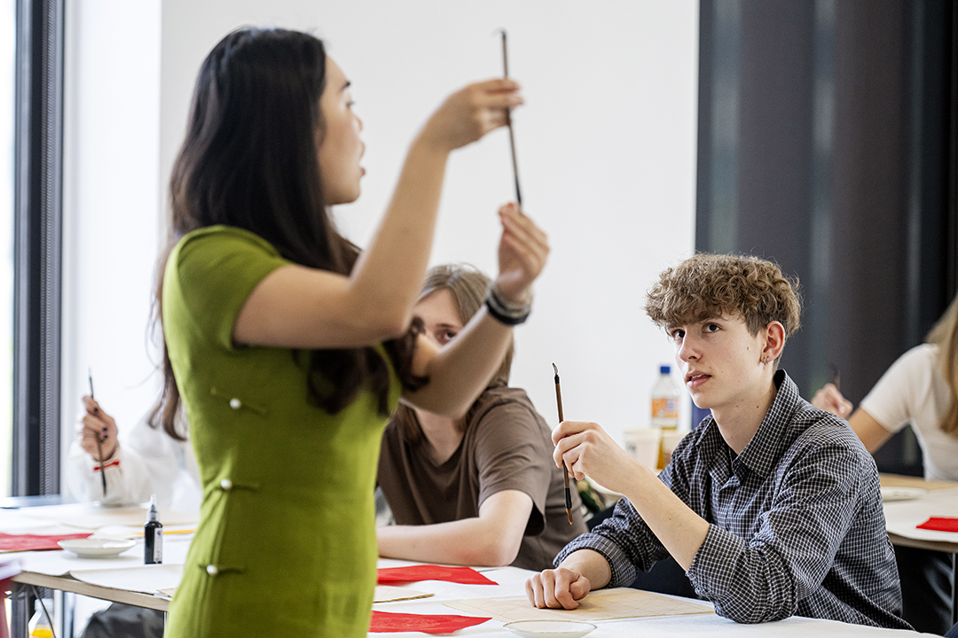 Underviser fra IBA Confucius Institute, der viser kaligrafipen frem.