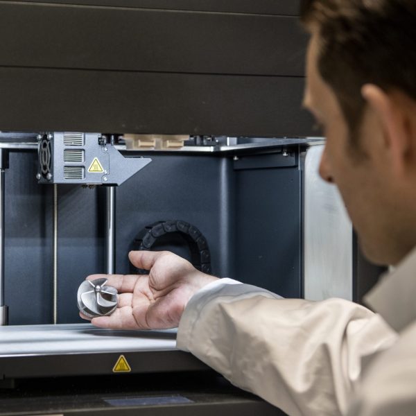 Anders fra IBA Nexttech med en hånd inde i en 3D-print maskine.