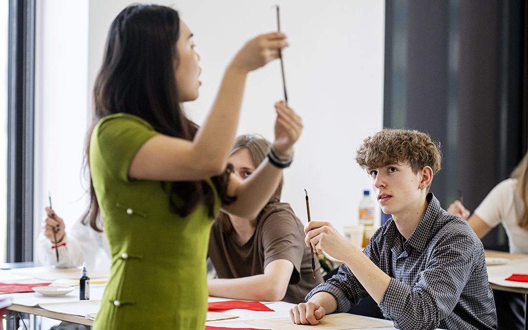 Underviser fra IBA Confucius Institute, der viser kaligrafipen frem.