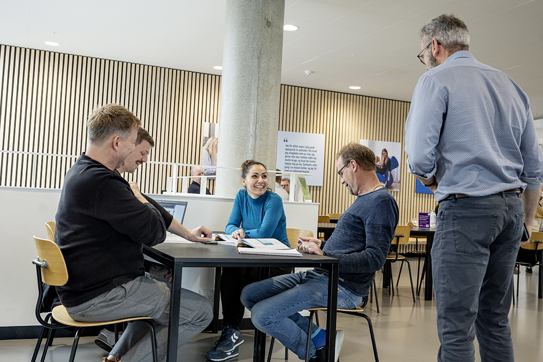 Studerende om et bord midt i gruppearbejde.