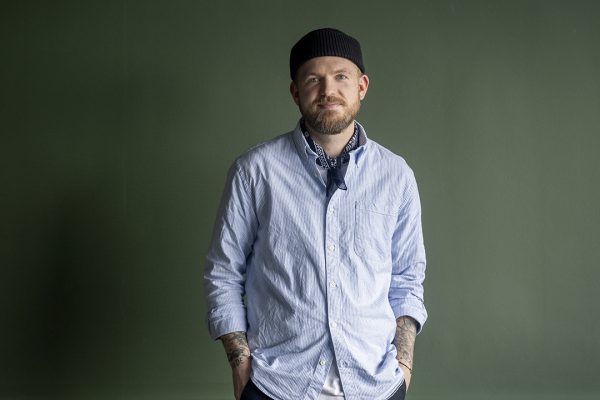 Portrætfoto af Emil foran en grøn væg