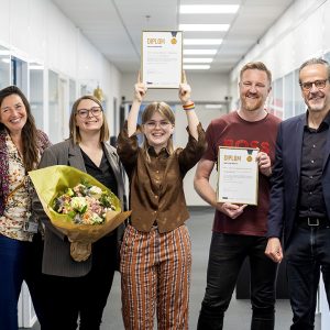 Foto af Line, med sit diplom og praktikvejleder samt uddannelseschef på IBA