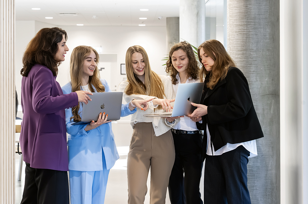 Phoyo of 4 students and their lecturer standing with a laptop